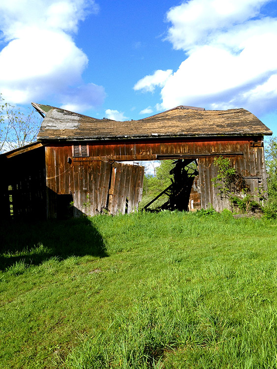 Image of a disintegrating barn with grass and clouds